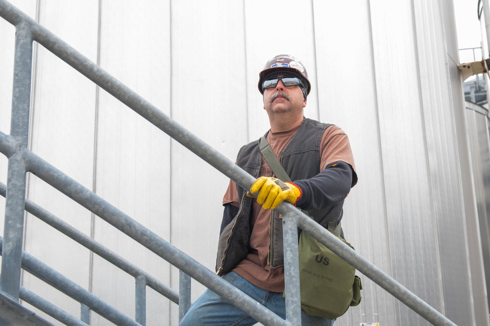 Industrial hazardous-site worker near storage tanks, used as context for intrinsically safe walkie talkie planning.